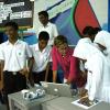 Group of kids and teacher gather around a laptop.